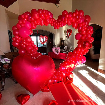 Vibrant 8ft red double-layer balloon heart arch, perfect party photo booth backdrop with red carpet.