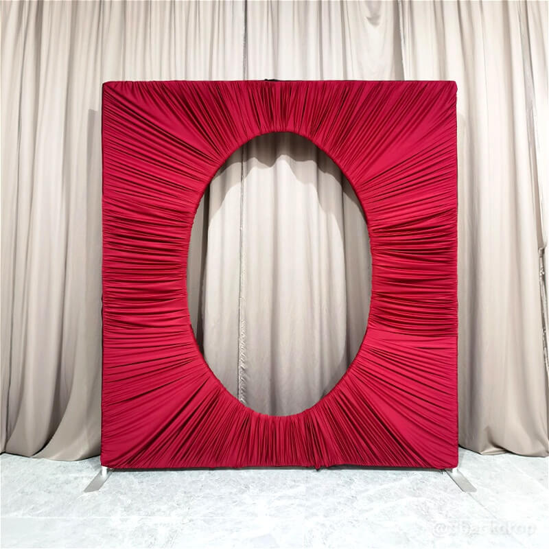 7x8ft square deep red ruched fabric backdrop stand with a prominent central oval cutout for events.