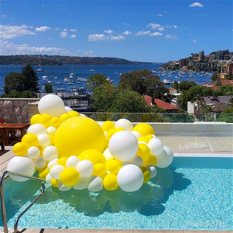 Big yellow and white matte inflatable balls floating as reusable party decor in a pool.